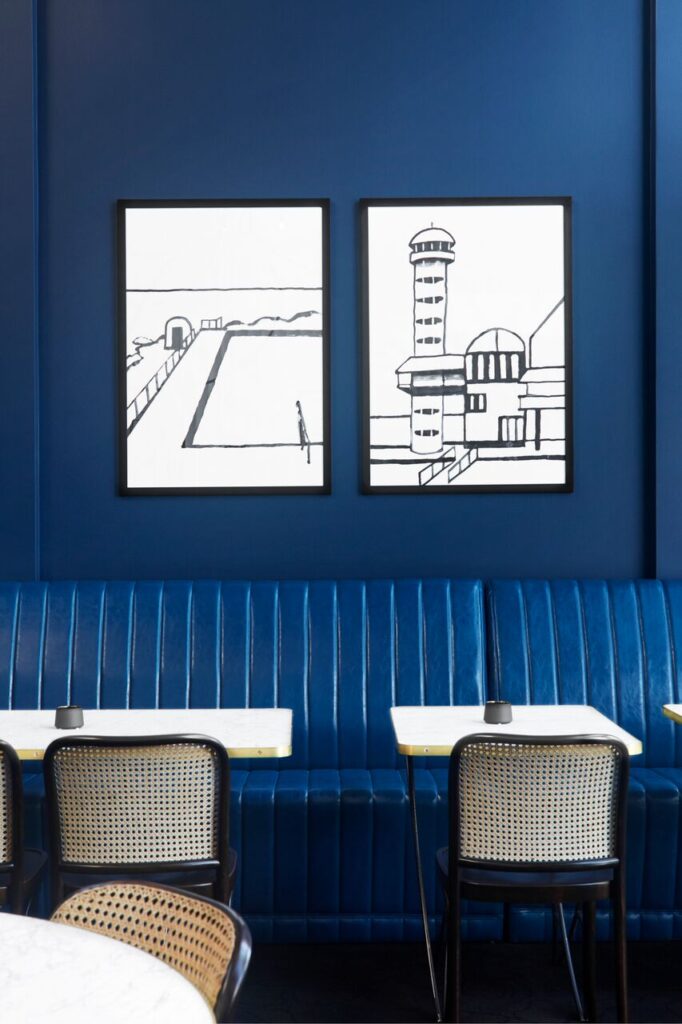 Blue banquette seating with framed black-and-white artwork