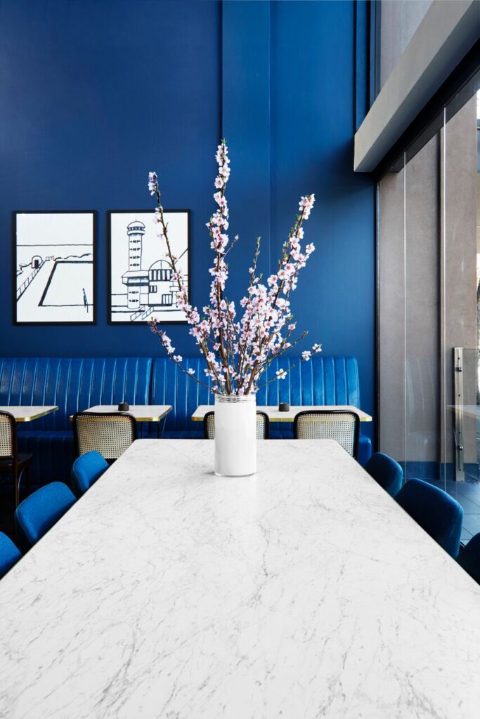 Modern dining space with deep blue walls, a long white marble table