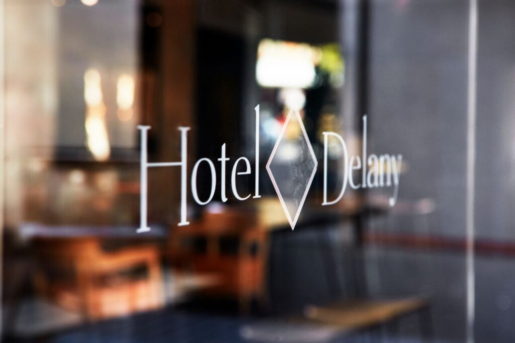 Close-up of a glass door with the ‘Hotel Delany’ logo